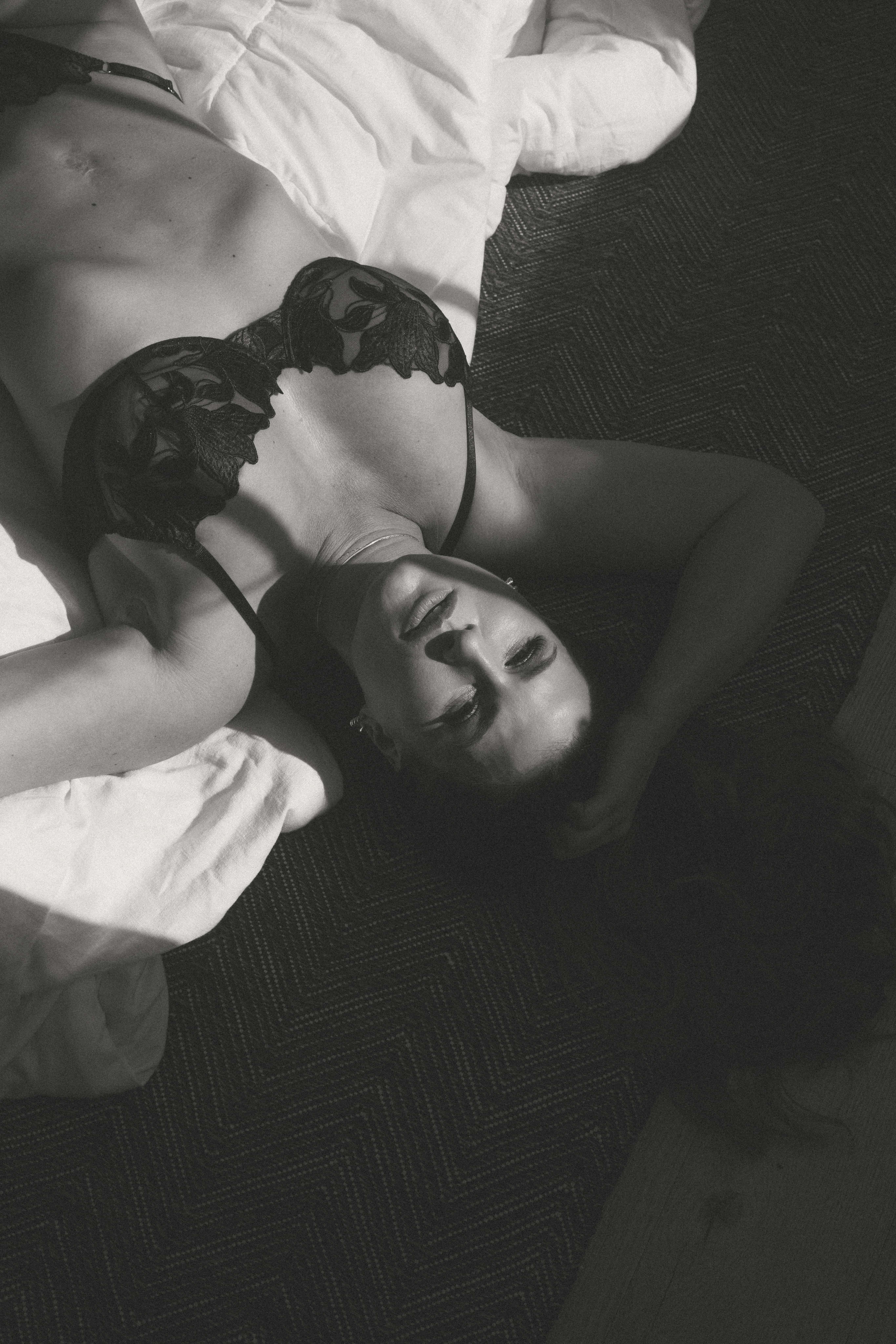 a woman laying on a bed with shadows across her skin during a maryland boudoir photography session 