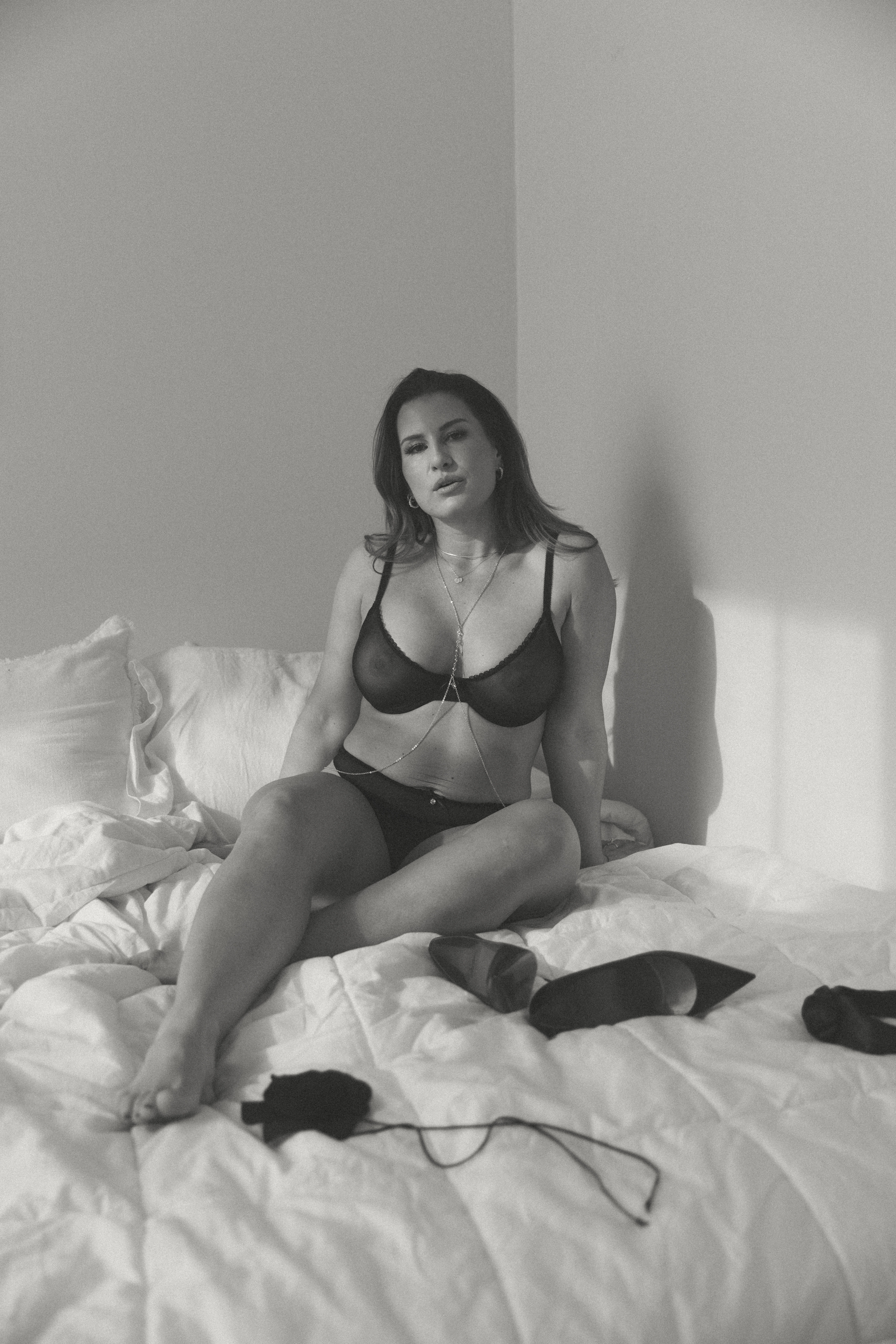 a woman in lingerie sitting on a bed in studio during a maryland boudoir photography session 