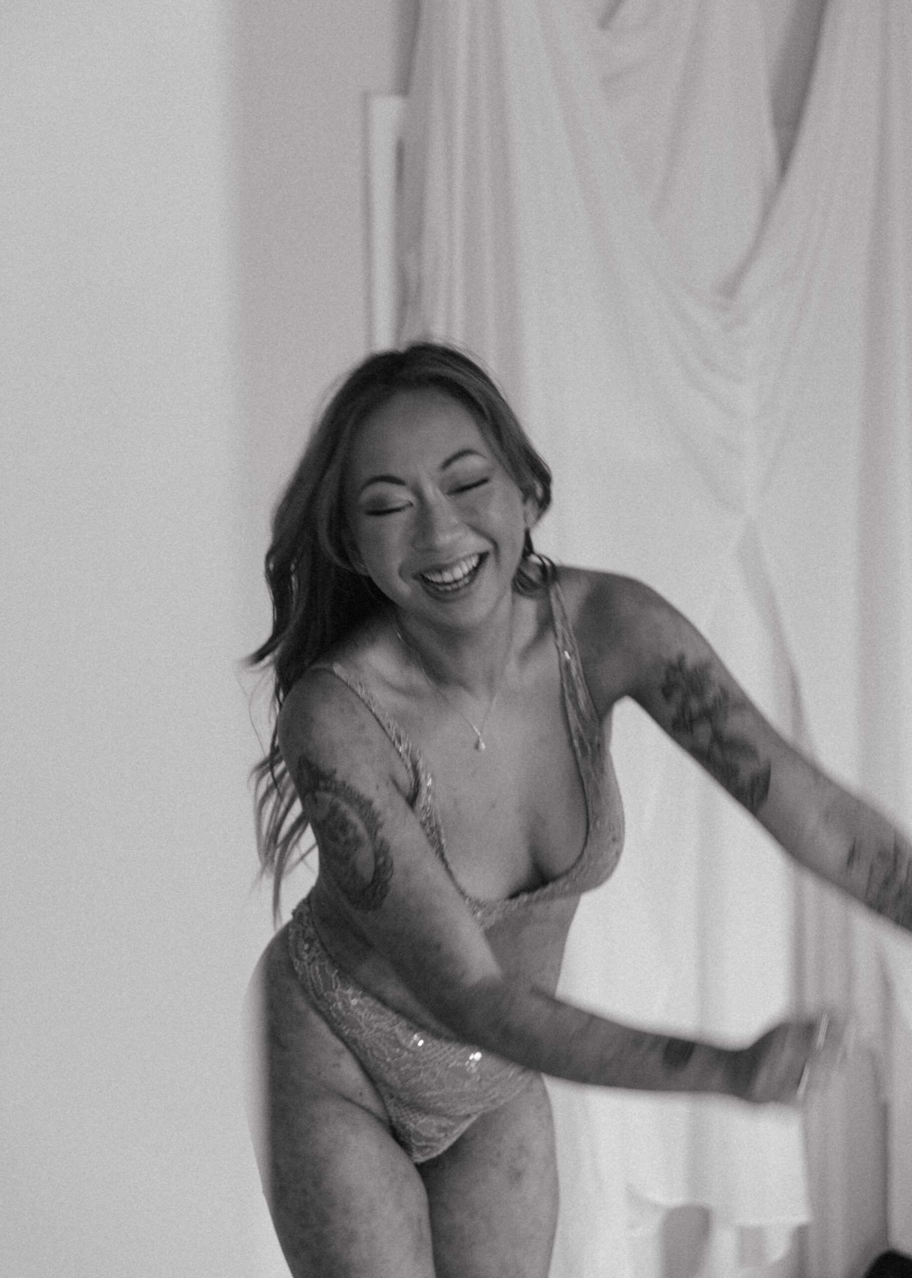 a woman in lingerie laughing during an artistic collaboration photoshoot