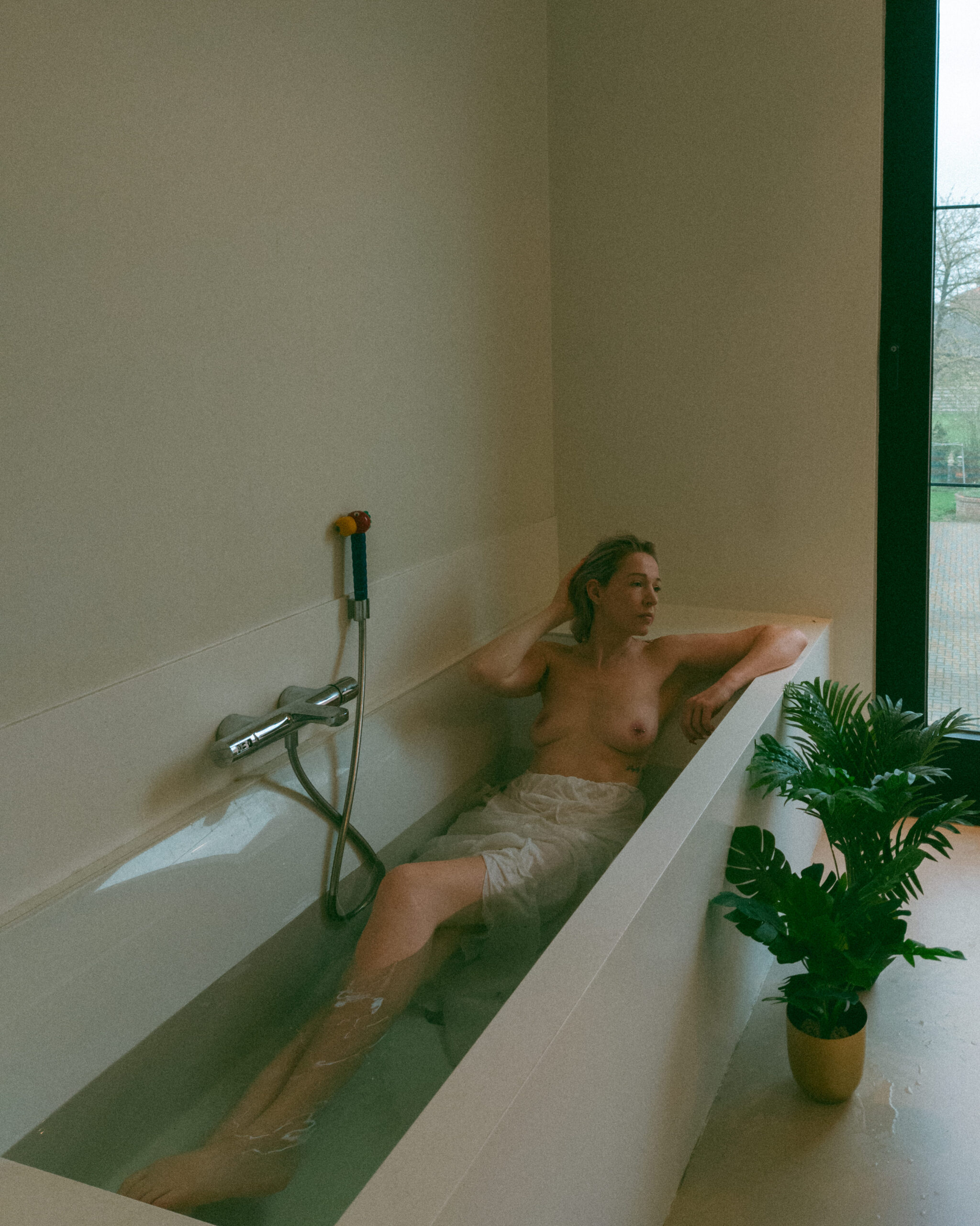 a woman wearing a skirt taking a bath during an intimate portrait photography session at her home