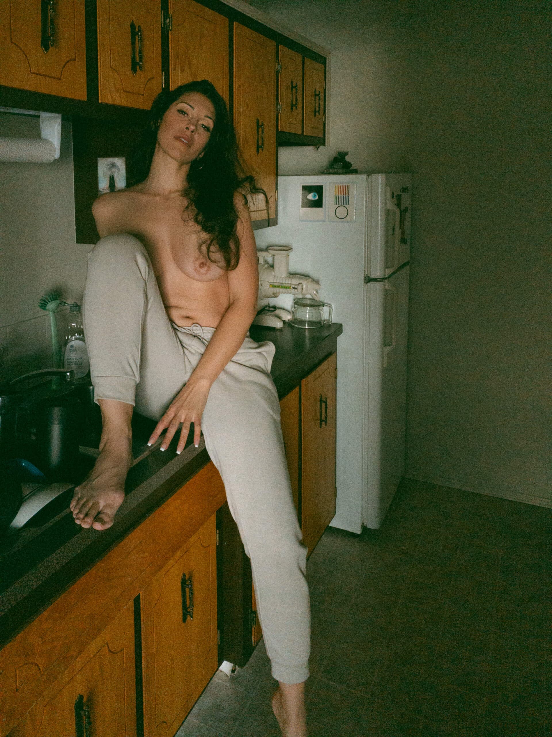 a topless woman sitting on the kitchen counter during at home boudoir photos 